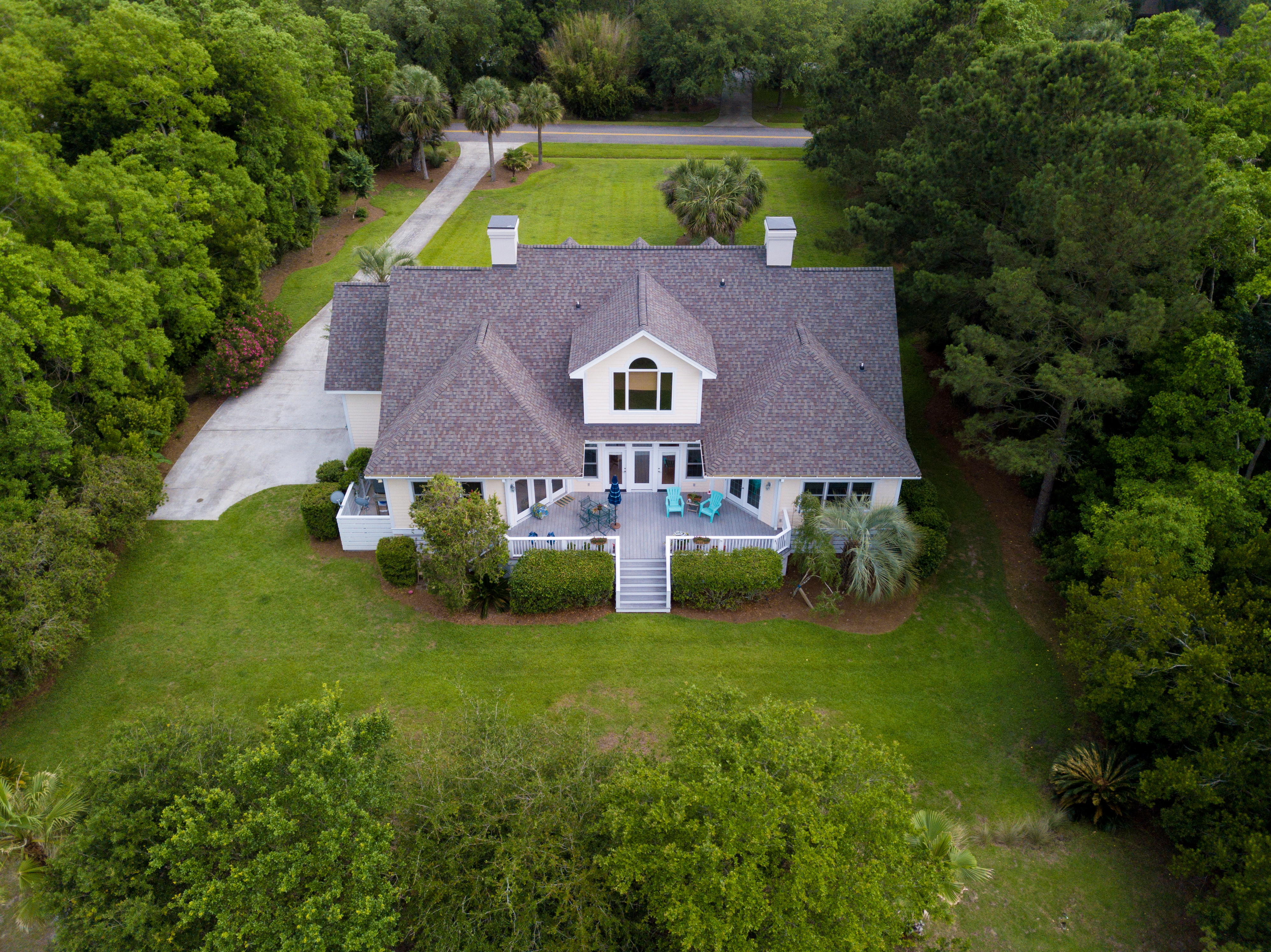 Aerial view of large home with new roof on wooded grassy propert