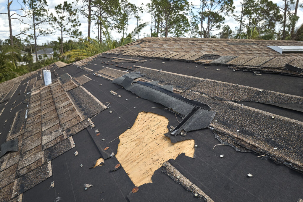 Damaged house roof with missing shingles after hurricane Ian in Florida.