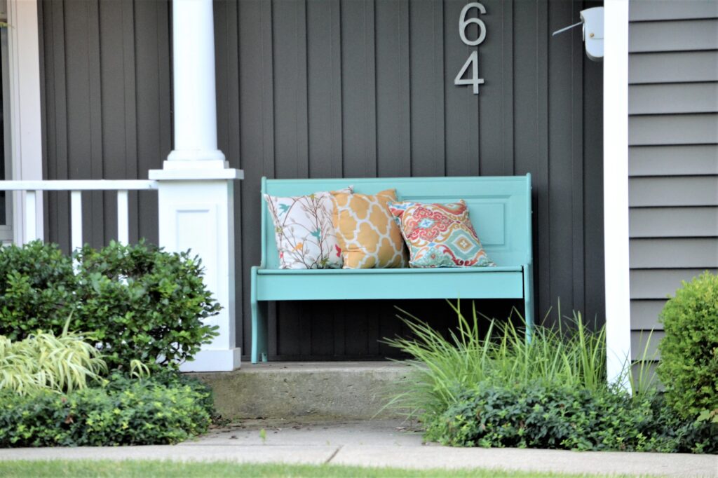 Painted bench and decorative pillows on the front porch entrance home sweet home